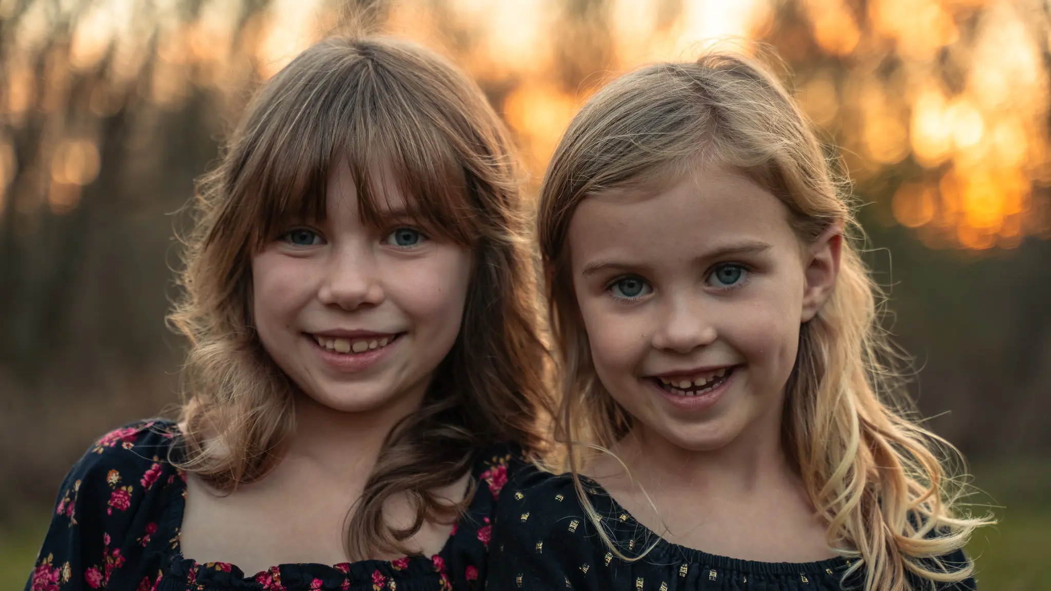 Two young sisters smiling at golden hour